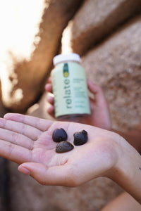 photo of blurred relate daily immunity daily supplement bottle and hand held out in focus with 3 gummies in the hand. 